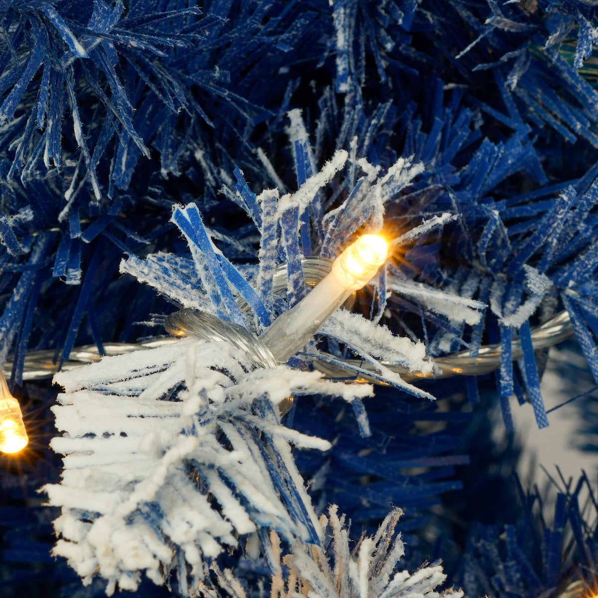 Warm LED light glowing on a blue flocked branch