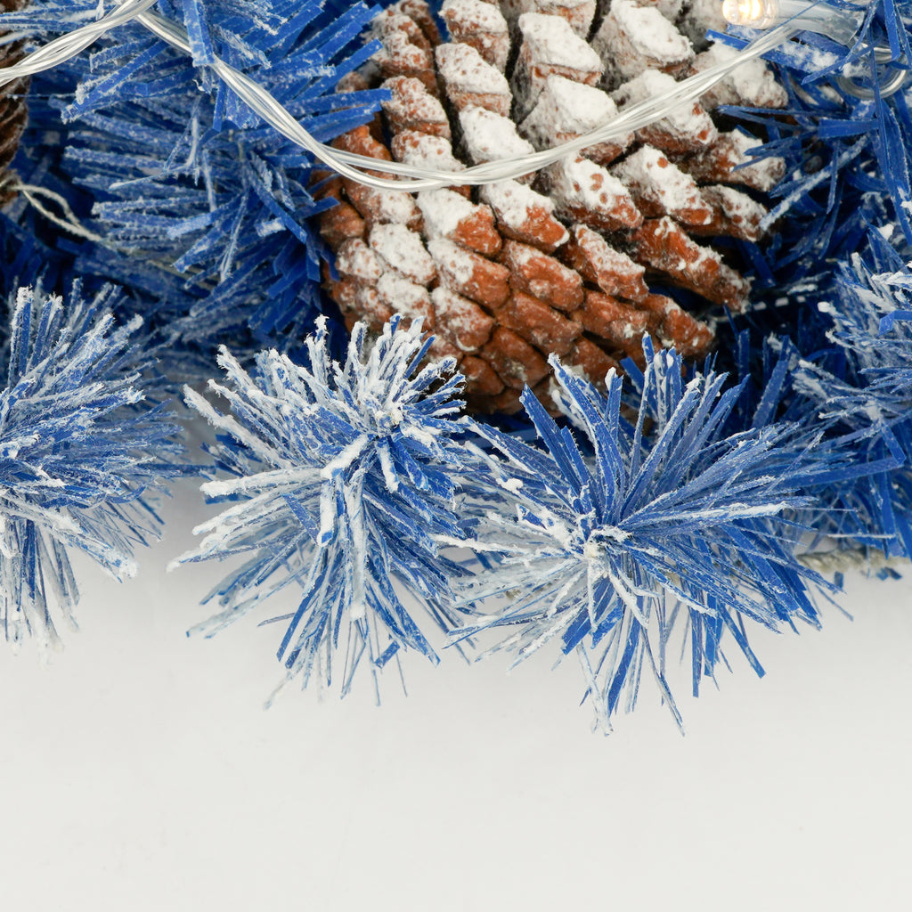 Blue branches with a pine cone and string lights, close-up