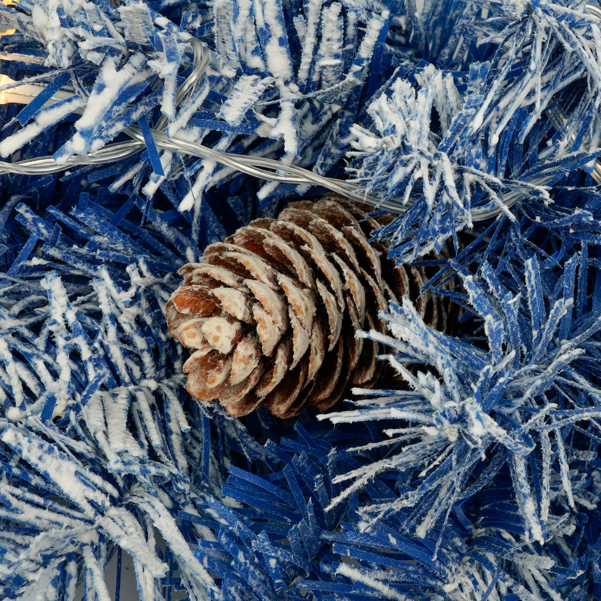 Pine cone nestled in blue flocked branches