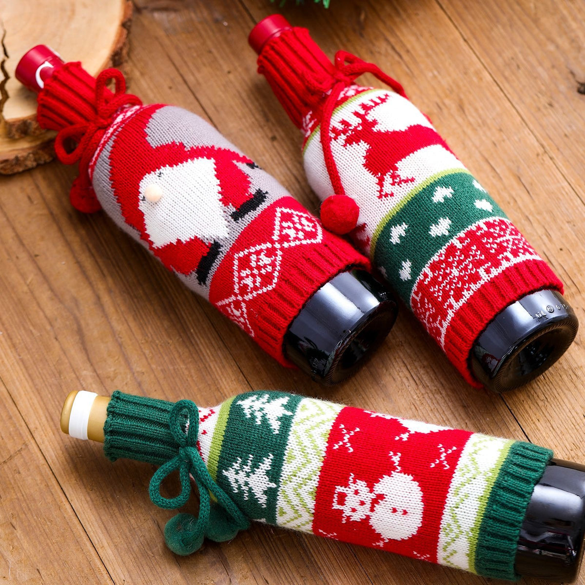 Knitted wine bottle covers in Santa, reindeer and snowman designs, flat lay