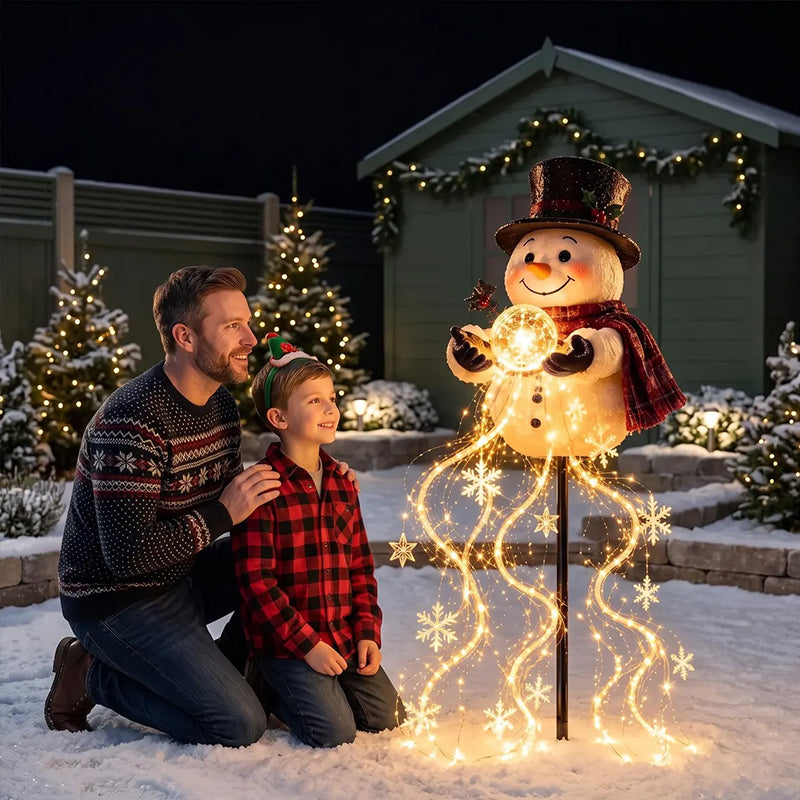 Father and son kneeling by the snowman stake light in the snow