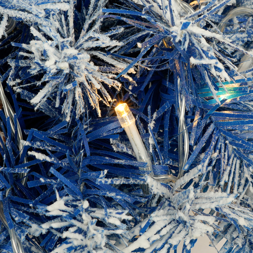 Blue flocked branch with a warm LED bulb, close-up